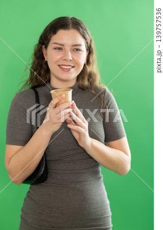 Young woman drinking coffee in front of green screen Young woman drinking coffee in front of green screen 139757536