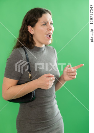Young woman angry and yelling in front of green screen 139757547