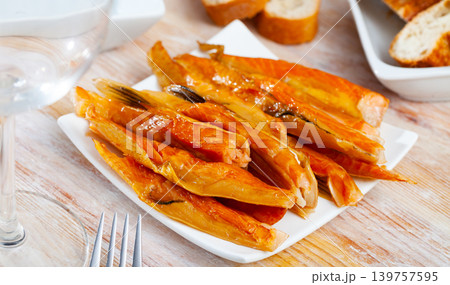 Smoked salmon belly strips on plate on wooden table 139757595
