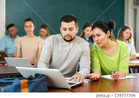 Woman and man university students using laptop and exercising together Woman and man university students using laptop and exercising together 139757706
