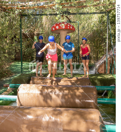 People trying to pass water obstacle course in adventure park People trying to pass water obstacle course in adventure park 139757714