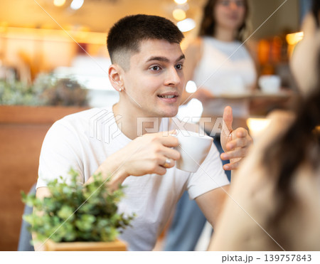 Guy chats with a woman in a coffee shop Guy chats with a woman in a coffee shop 139757843
