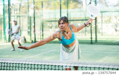 Young woman in skirt playing padel tennis on court Young woman in skirt playing padel tennis on court 139757844