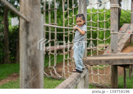 preschool child girl walking on a wooden balancing bridge at outdoor playground preschool child girl walking on a wooden balancing bridge at outdoor playground 139758196