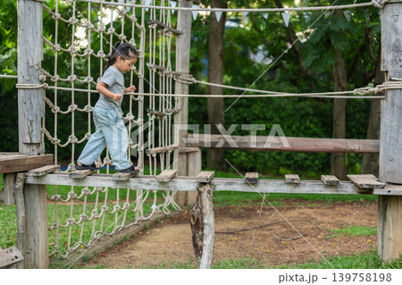 preschool child girl walking on a wooden balancing bridge at outdoor playground 139758198