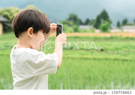 田舎の風景をスマホで写真を撮る男の子,子供の横顔 田舎の風景をスマホで写真を撮る男の子,子供の横顔 139758662