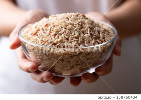 Organic Thai brown rice in a glass bowl holding by woman hand, Asian food ingredient Organic Thai brown rice in a glass bowl holding by woman hand, Asian food ingredient 139760434