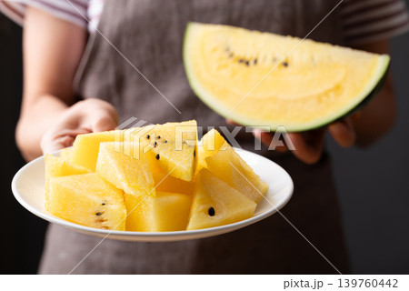 Sliced yellow watermelon on white plate holding by woman hand 139760442