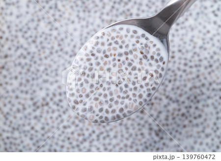 Close up of chia seeds soaking in milk with spoon, preparation for healthy chia pudding, Top view Close up of chia seeds soaking in milk with spoon, preparation for healthy chia pudding, Top view 139760472