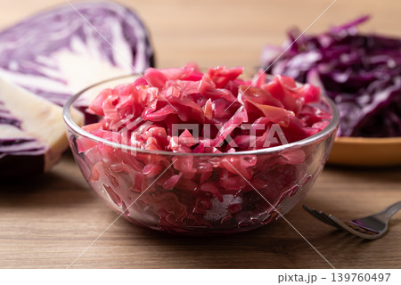 Red cabbage sauerkraut in a glass bowl with fresh red cabbage on wooden background 139760497