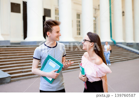 Two happy students walking and having a talk near old campus after classes, they are eager to share latest news to one another 139760587
