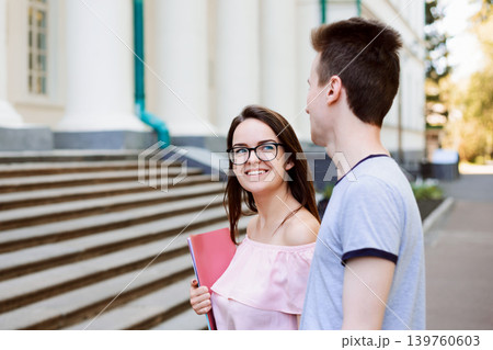 Lovely girl student with beautiful smile looks to her boyfriend and heading to the classes. Two students in love attending lectures of a conventional university 139760603
