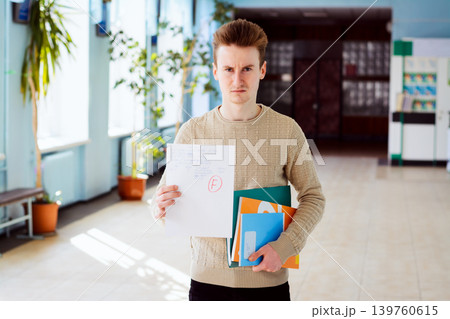 Failed test or exam and angry student in corridor of university with learnng materials 139760615