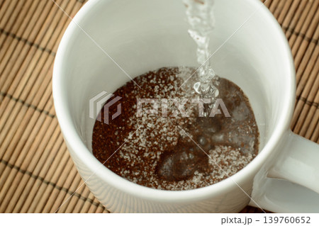 Pouring boiling water to the cap with coffee and sugar. Making coffee in the morning. Pouring boiling water to the cap with coffee and sugar. Making coffee in the morning. 139760652