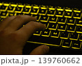 Man's hand typing on keyboard with yellow backlight 139760662