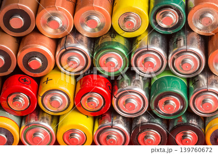 Stack of used batteries on a red background. Background of alkaline battery AA size Stack of used batteries on a red background. Background of alkaline battery AA size 139760672
