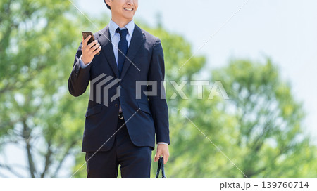 スマートフォンを持って屋外を歩く男性ビジネスマン 139760714