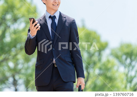スマートフォンを持って屋外を歩く男性ビジネスマン 139760716