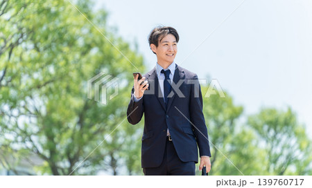 スマートフォンを持って屋外を歩く男性ビジネスマン スマートフォンを持って屋外を歩く男性ビジネスマン 139760717