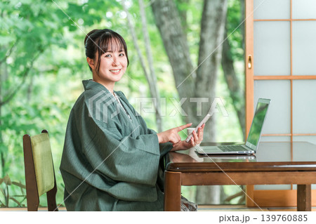 温泉旅館の部屋でパソコンとスマホで仕事をする浴衣姿の女性 温泉旅館の部屋でパソコンとスマホで仕事をする浴衣姿の女性 139760885