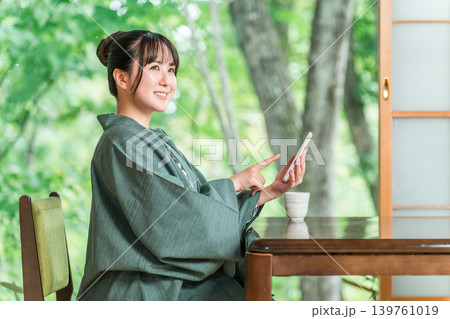 旅館の和室でスマホを見る浴衣姿の若いアジア人女性 旅館の和室でスマホを見る浴衣姿の若いアジア人女性 139761019
