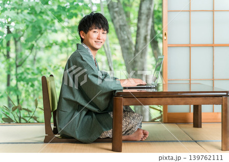 温泉旅館の部屋でパソコンで仕事をする浴衣姿の男性 温泉旅館の部屋でパソコンで仕事をする浴衣姿の男性 139762111