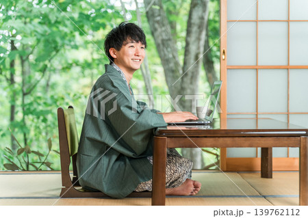 温泉旅館の部屋でパソコンで仕事をする浴衣姿の男性 温泉旅館の部屋でパソコンで仕事をする浴衣姿の男性 139762112