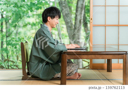 温泉旅館の部屋でパソコンで仕事をする浴衣姿の男性 温泉旅館の部屋でパソコンで仕事をする浴衣姿の男性 139762113
