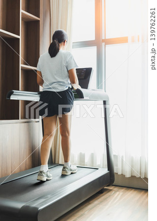 Active woman walking on a treadmill at home gym. Active woman walking on a treadmill at home gym. 139762261