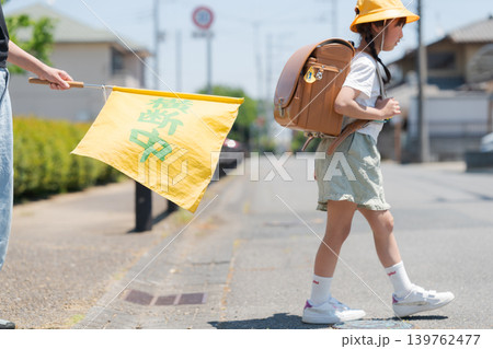 登下校中の小学生と交通安全見守りの旗 登下校中の小学生と交通安全見守りの旗 139762477