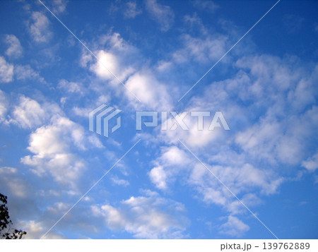 Bright blue sky filled with soft white clouds creating a peaceful natural background. Scenic daytime atmosphere with fluffy cloud formations and clear weather in a tranquil outdoor scene Bright blue sky filled with soft white clouds creating a peaceful natural background. Scenic daytime atmosphere with fluffy cloud formations and clear weather in a tranquil outdoor scene 139762889
