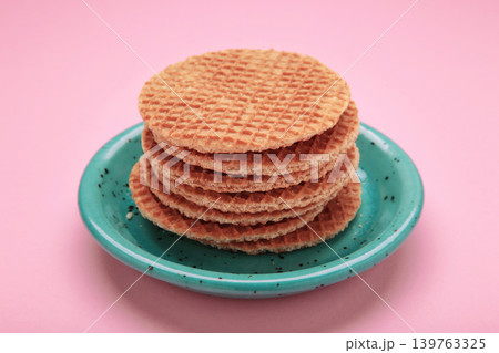 Stack of Dutch stroop wafel cookies or caramel waffles on plate on pink background. Space for text 139763325
