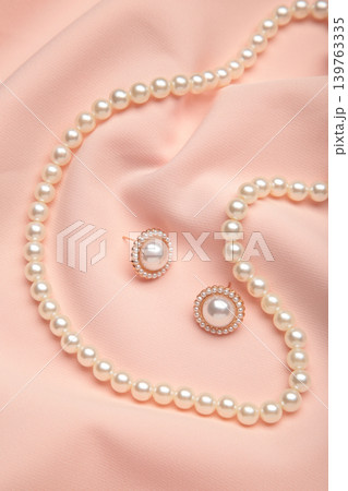 Beautiful pearl bracelet, earring, and necklace on pink texture background. Vertical photo 139763335