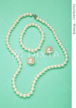 Beautiful pearl earring and necklace on mint background. Vertical photo Beautiful pearl earring and necklace on mint background. Vertical photo 139763352