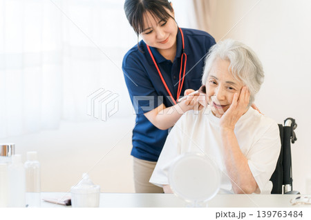 介護施設で介護美容,訪問美容,メイクセラピーを受けるシニア女性 介護施設で介護美容,訪問美容,メイクセラピーを受けるシニア女性 139763484