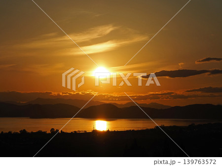 猪苗代湖上空のに輝くオレンジ色の夕日。湖面が輝き、印象的で綺麗だ。 猪苗代湖上空のに輝くオレンジ色の夕日。湖面が輝き、印象的で綺麗だ。 139763572