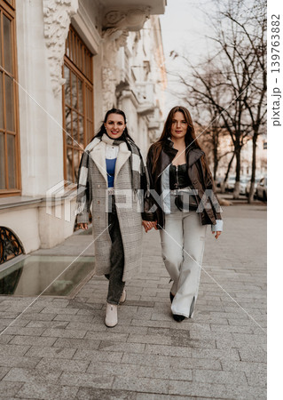 Women walking fashion strolling past ornate buildings wearing trendy winter outfits showcasing urban friendship and lifestyle 139763882