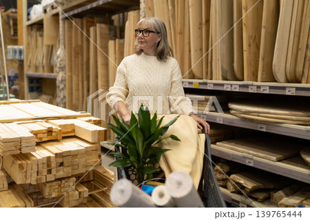 Senior woman pushing shopping cart with plant and lumber in a hardware store 139765444