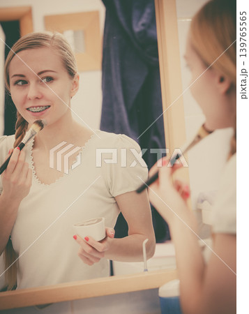 Happy young woman applying mud mask on face 139765565
