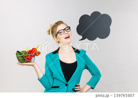 Woman holds shopping cart with vegetables, copy space Woman holds shopping cart with vegetables, copy space 139765807