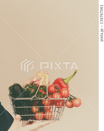 Hand holds shopping cart with vegetables 139767061