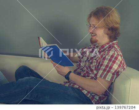 Man relaxing on sofa reading book Man relaxing on sofa reading book 139767284