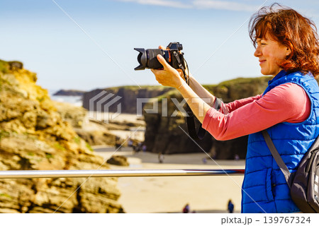 Woman with camera at Cathedral Beach in Spain. Woman with camera at Cathedral Beach in Spain. 139767324