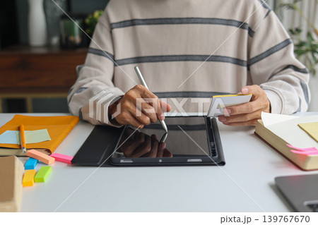 Man organizing schedule with sticky notes and digital tablet at home. Man organizing schedule with sticky notes and digital tablet at home. 139767670