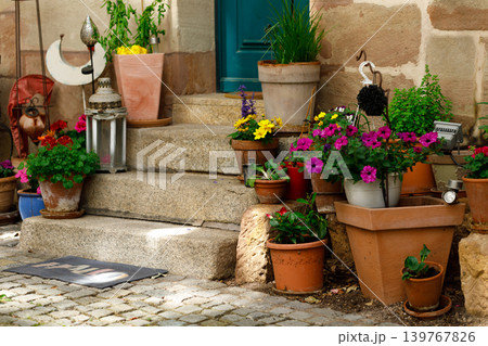 Terracotta ceramic flower pots with green plants placed at the entrance of a house. Cozy outdoor home decor with natural warm tones and rustic style. Terracotta ceramic flower pots with green plants placed at the entrance of a house. Cozy outdoor home decor with natural warm tones and rustic style. 139767826