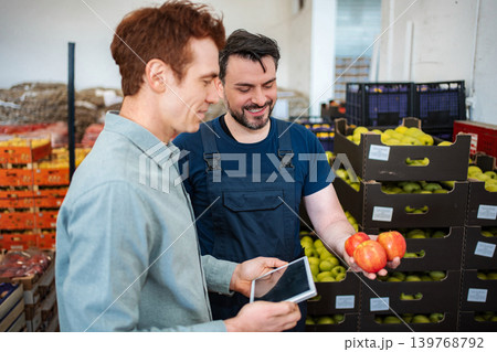 Worker showing fresh apples to customer in warehouse Worker showing fresh apples to customer in warehouse 139768792