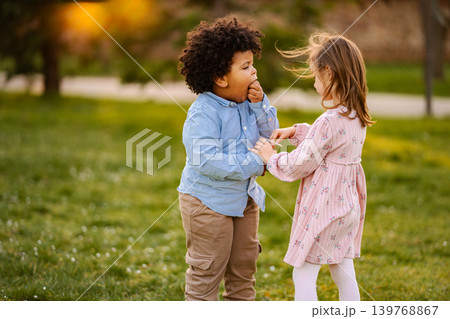 Diverse children sharing snack enjoying outdoor park playtime Diverse children sharing snack enjoying outdoor park playtime 139768867