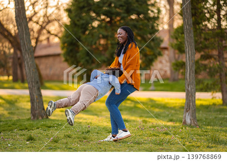 Mother and son playing, laughing, and spinning in park 139768869
