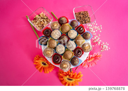 Plate of energy balls and truffles with nuts on pink background Plate of energy balls and truffles with nuts on pink background 139768878