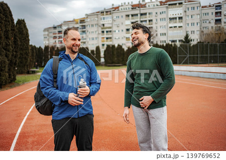 Two friends laughing on running track after exercise Two friends laughing on running track after exercise 139769652